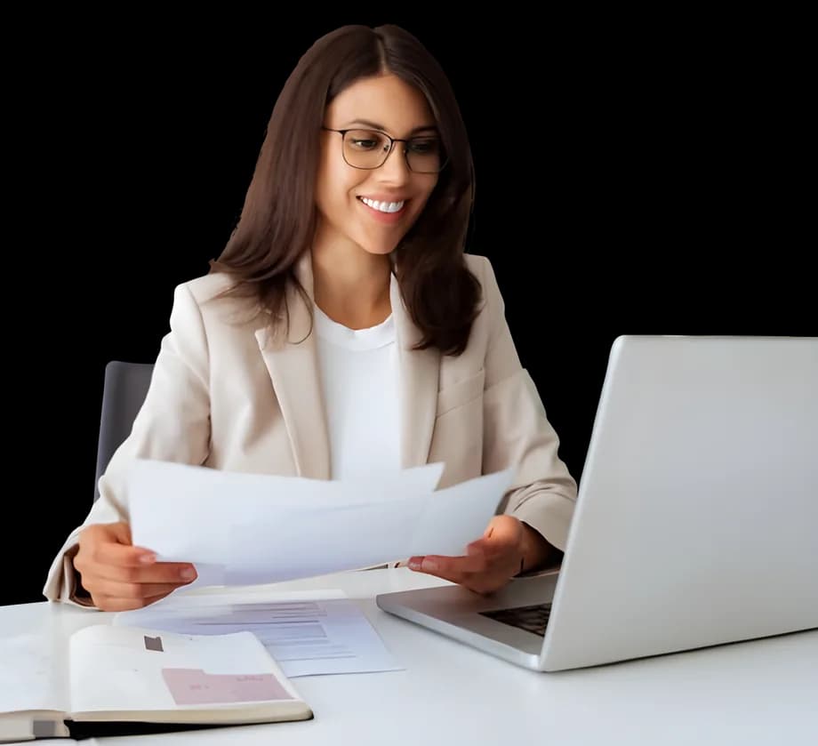 A woman reviewing documents at her laptop